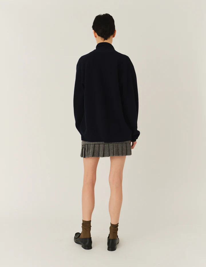 Model wearing The Garment Taylor Mini Plaid Skirt styled with a knit sweater and boots